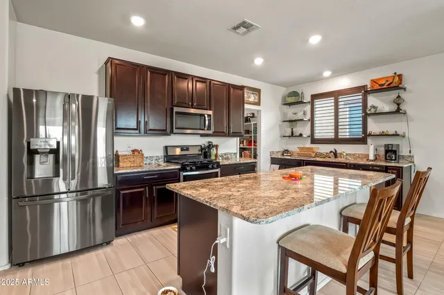 a kitchen with stainless steel appliances granite countertop a refrigerator a stove a sink a microwave and a refrigerator