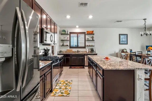 a kitchen with stainless steel appliances granite countertop a stove top oven a sink dishwasher a refrigerator and a stove