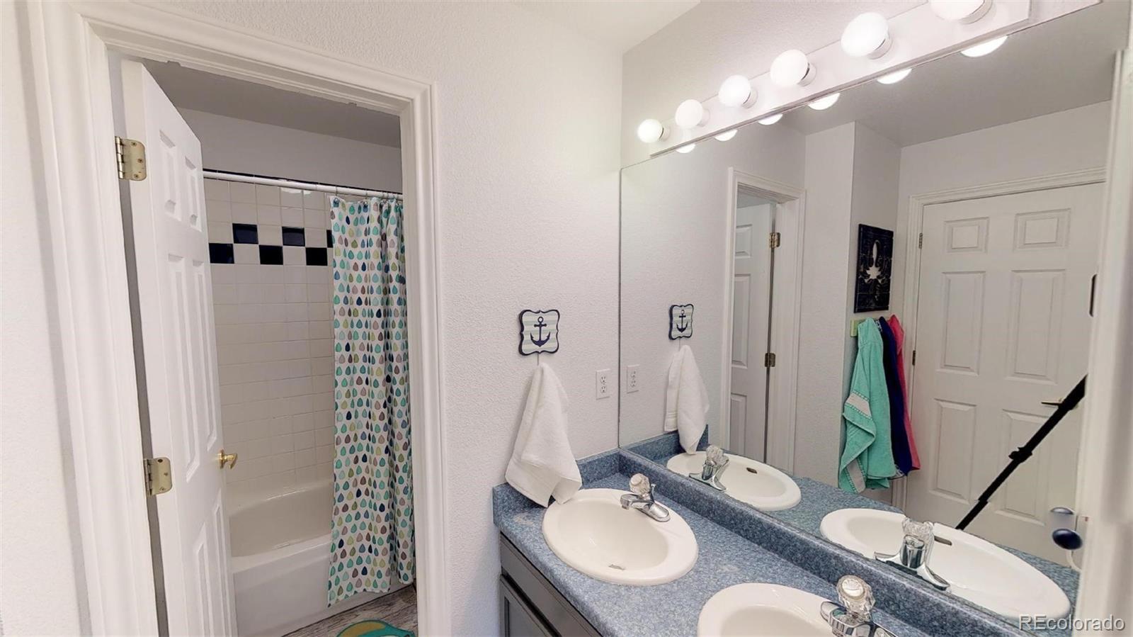 601 Rider Ridge Drive Longmont, CO 80504 - Photo 21 of 32 a bathroom with a granite countertop sink a mirror a vanity and a shower
