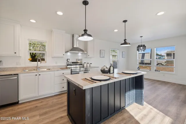 a kitchen with stainless steel appliances granite countertop a sink a stove and a wooden floors