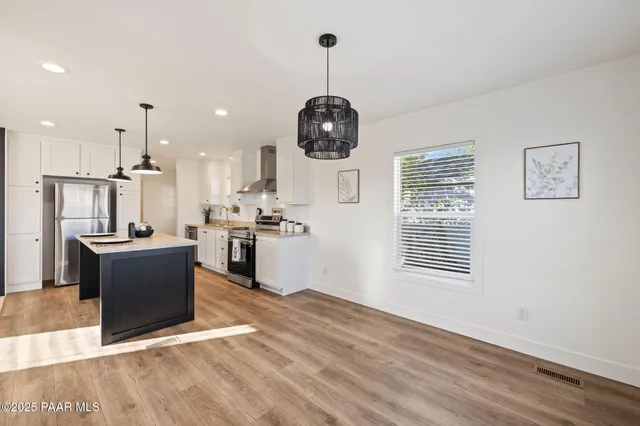 a kitchen with stainless steel appliances granite countertop a refrigerator a stove top oven a sink dishwasher and a stove with wooden floor