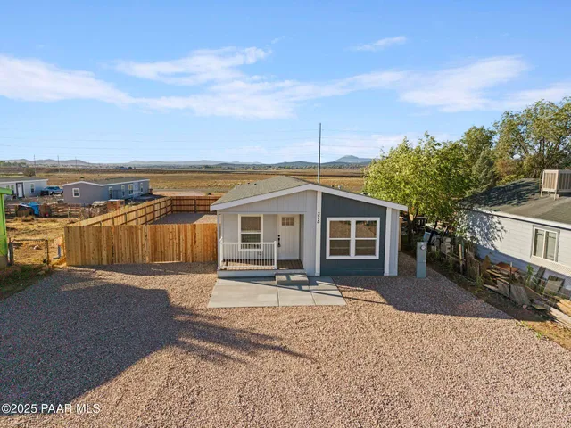a front view of house with yard and trees in the background
