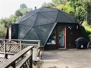 a front view of a house with barbeque grill and wooden fence