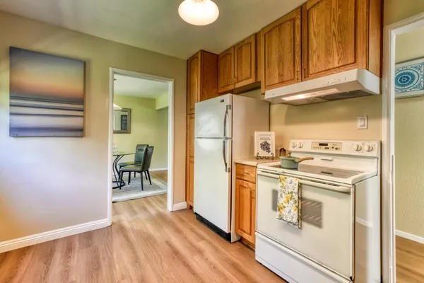 a kitchen with a refrigerator a stove and a wooden floor
