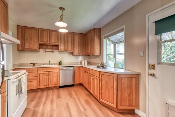 a kitchen with granite countertop white cabinets a sink a window and appliances