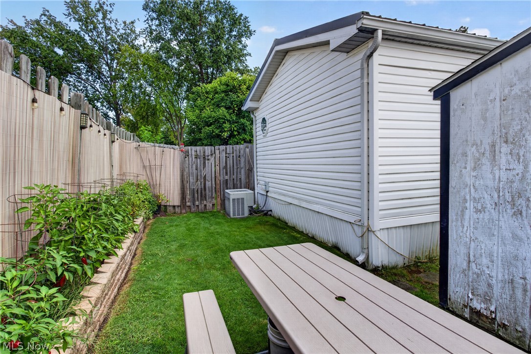 35157 Center Ridge Road, Unit 153 North Ridgeville, OH 44039 - Photo 33 of 35 Fenced backyard featuring a raised garden bed with stone retaining wall, manicured lawn, and a utility shed