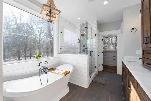 a bathroom with a tub a sink a mirror and a shower