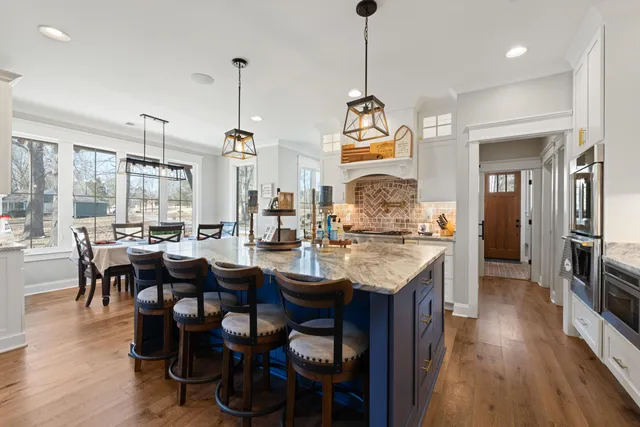 a open kitchen with stainless steel appliances granite countertop wooden floor dining table and chairs