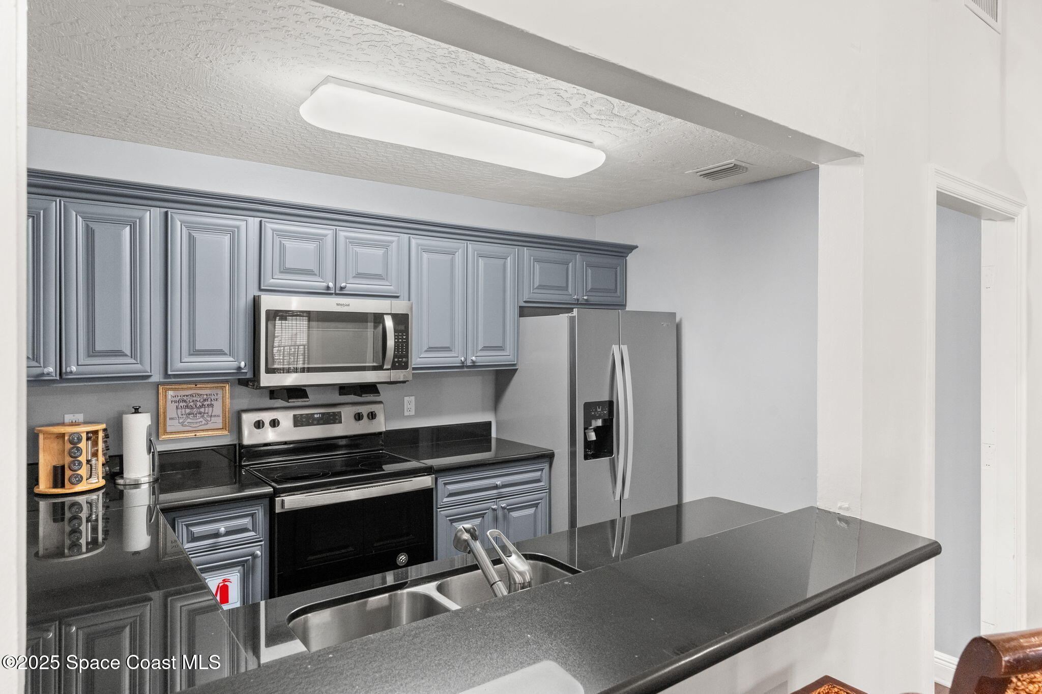 7667 North Wickham Road, Unit 518 Melbourne, FL 32940 - Photo 27 of 34 a kitchen with granite countertop a refrigerator stove and microwave