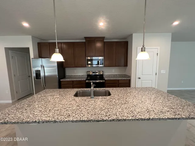 a kitchen with kitchen island a sink stainless steel appliances and a counter top space