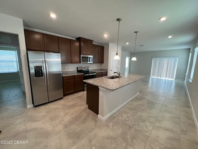 a large kitchen with stainless steel appliances kitchen island granite countertop a stove a sink a refrigerator a microwave and island
