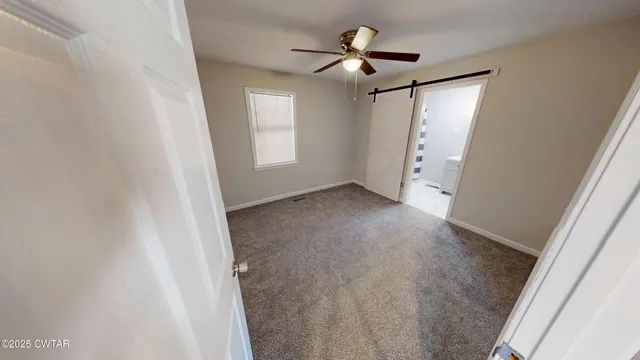 an empty room with windows and fan