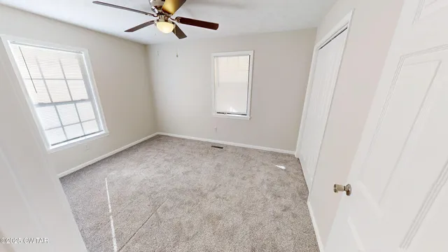 an empty room with windows and fan