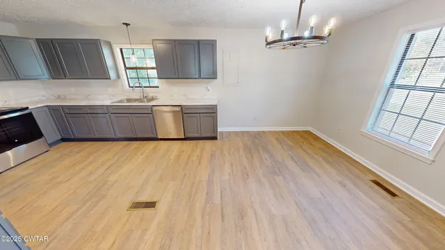 a kitchen with stainless steel appliances a sink cabinets and wooden floor