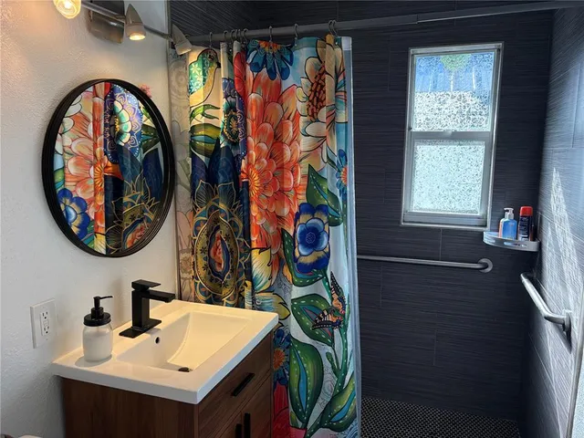 a bathroom with a sink a mirror and a painting on the wall