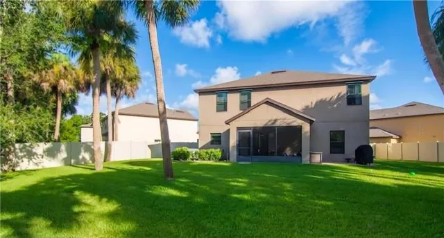 a view of a house with a big yard and palm trees