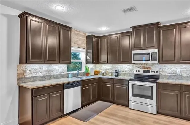 a kitchen with stainless steel appliances granite countertop a sink stove and refrigerator