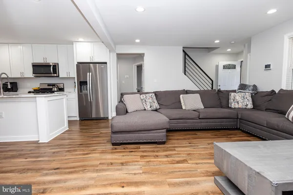 a living room with stainless steel appliances kitchen island granite countertop a couch and a view of living room