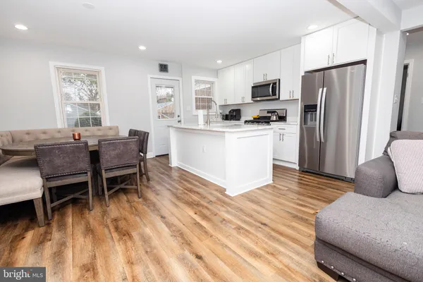 a kitchen with stainless steel appliances granite countertop a refrigerator a stove a microwave oven with a dining table and chairs with wooden floor