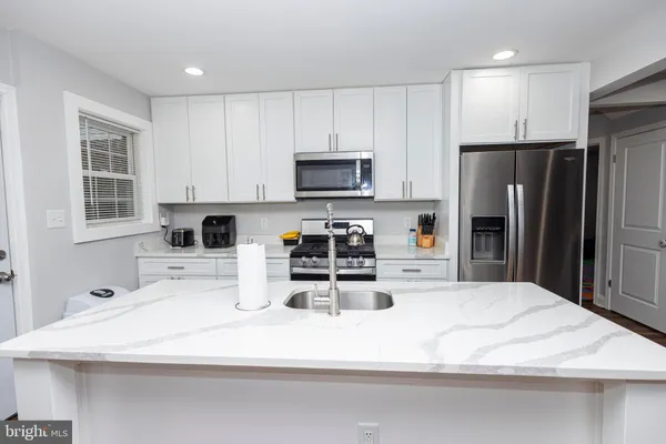 a kitchen with kitchen island a sink stainless steel appliances and cabinets