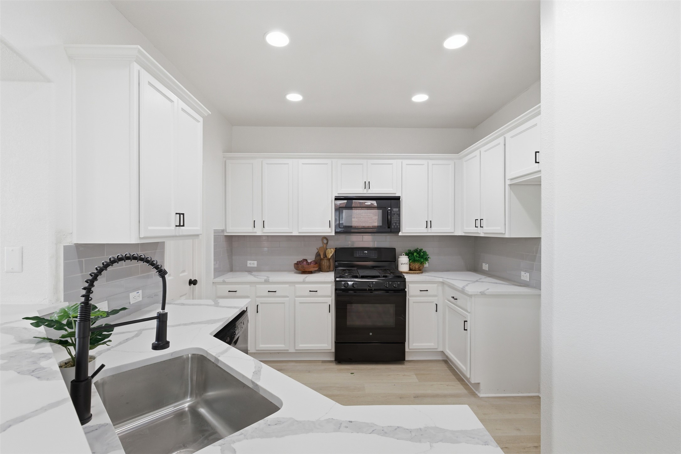 461 Hot Spring Valley Buda, TX 78610 - Photo 6 of 25 Well-appointed kitchen featuring white cabinetry, gray subway tile backsplash, and a stainless steel sink with a matte black faucet