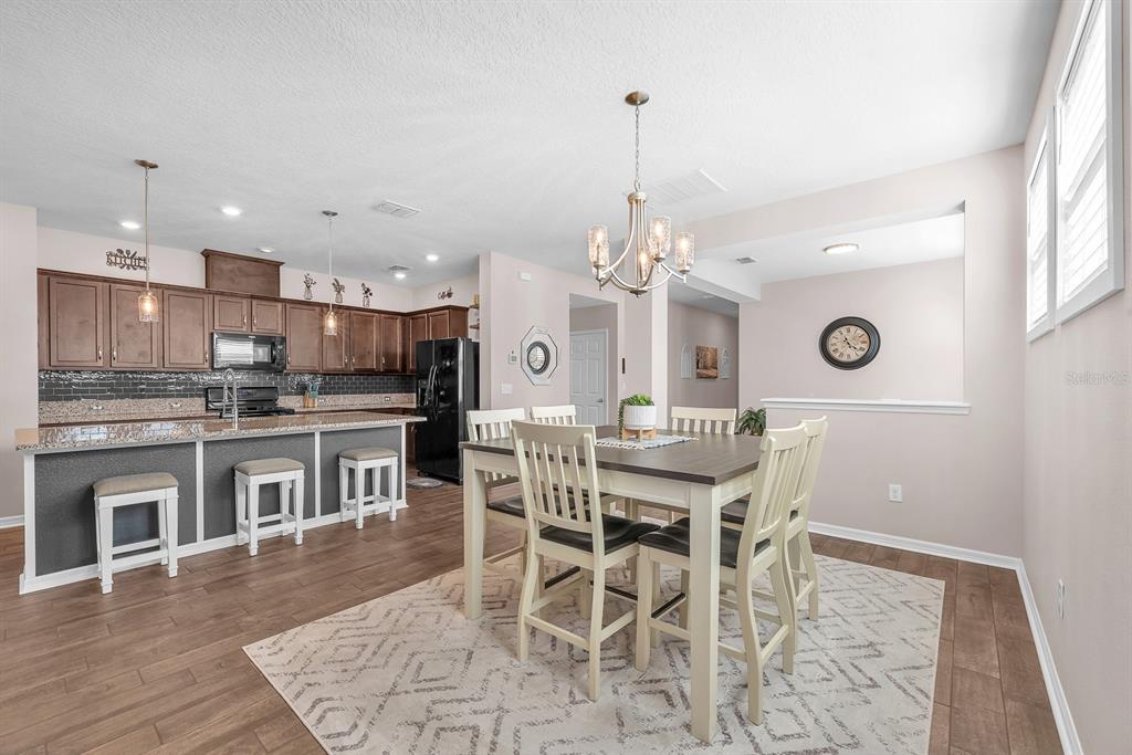 6230 Plover Meadow Street Lithia, FL 33547 - Photo 11 of 50 a kitchen with stainless steel appliances kitchen island granite countertop a dining table chairs and white cabinets