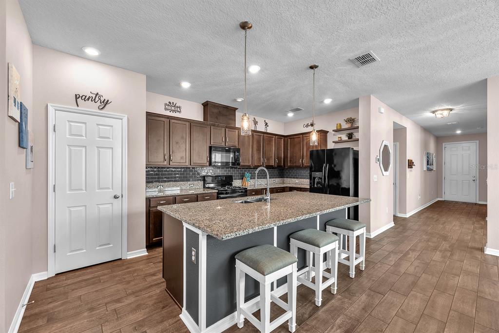 6230 Plover Meadow Street Lithia, FL 33547 - Photo 12 of 50 a kitchen with stainless steel appliances granite countertop a refrigerator oven a sink a dining table and chairs