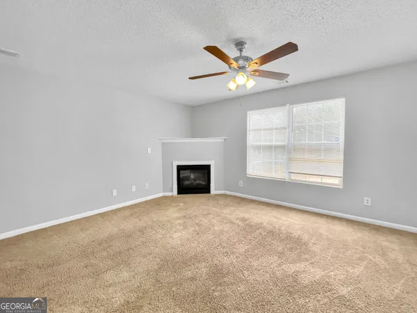 an empty room with windows and fan