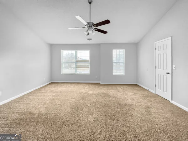 an empty room with windows and ceiling fan view