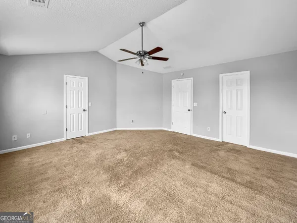an empty room with chandelier fan and windows