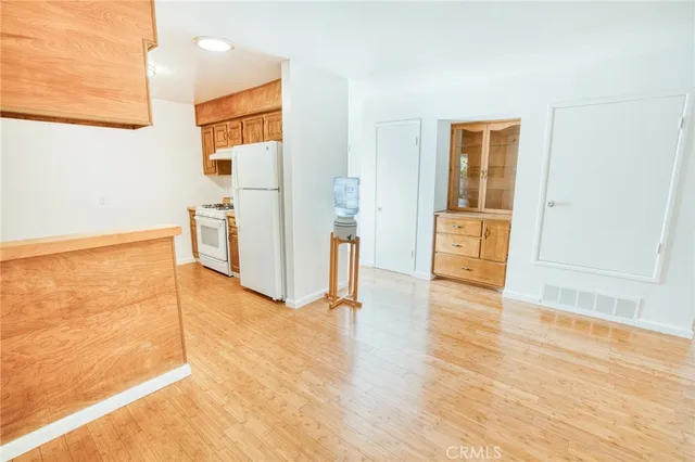 a view of a livingroom with wooden floor and a refrigerator