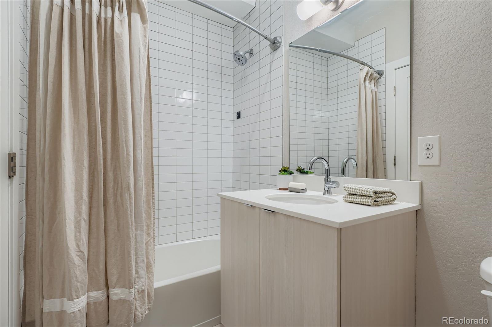 1261 Xavier Street Denver, CO 80204 - Photo 14 of 27 a bathroom with a sink a mirror and a shower