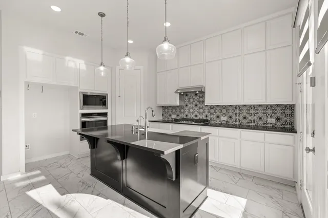 a kitchen with stainless steel appliances granite countertop a sink a stove and a refrigerator