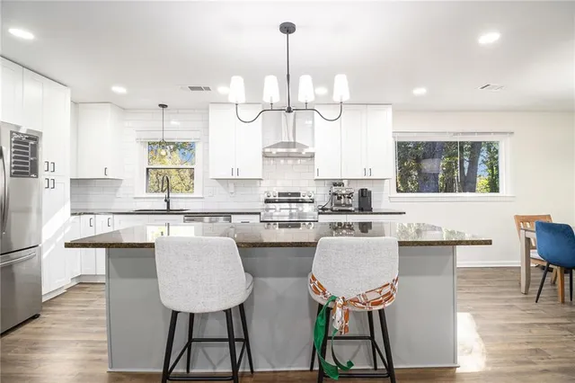 a kitchen with stainless steel appliances granite countertop a stove a sink dishwasher a dining table and chairs with wooden floor