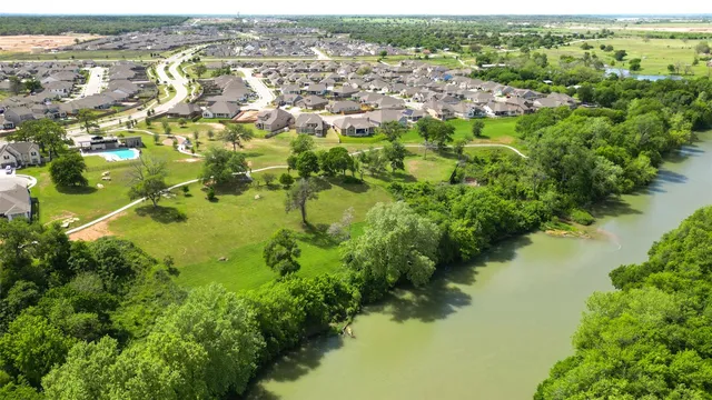 an aerial view of residential houses with outdoor space and trees all around