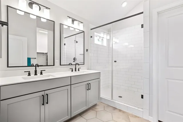 a bathroom with a double vanity sink mirror and shower