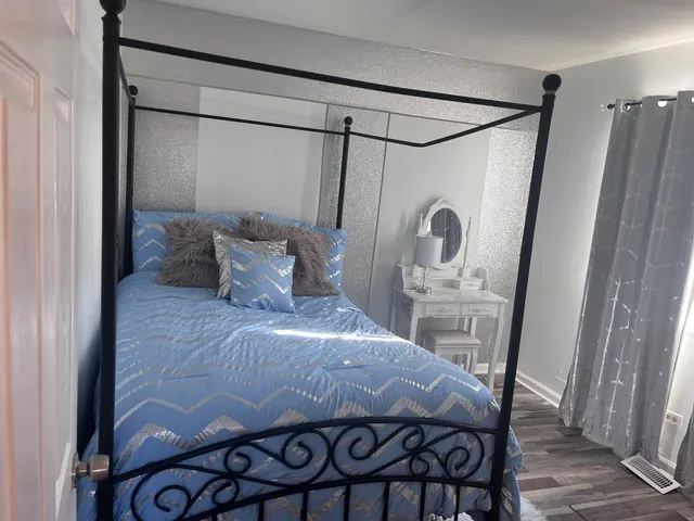 a bedroom with a bed a mirror on the dresser and floor