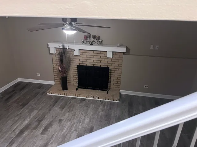 a view of an empty room with wooden floor fireplace and a window