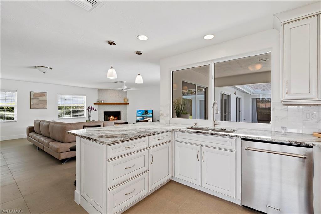740 Orchid Drive Naples, FL 34102 - Photo 11 of 33 a kitchen with granite countertop kitchen island white cabinets and white appliances