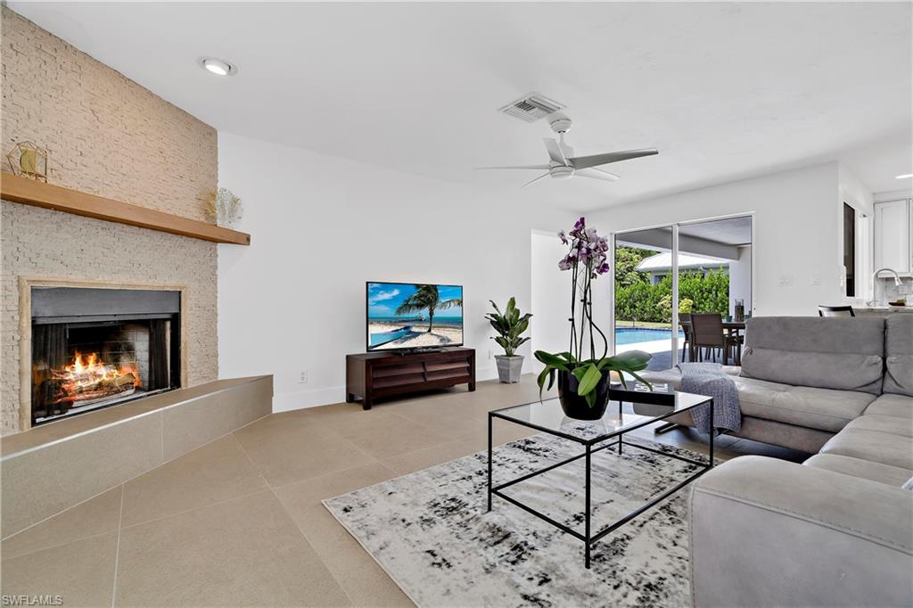 740 Orchid Drive Naples, FL 34102 - Photo 14 of 33 a living room with furniture a fireplace and a flat screen tv