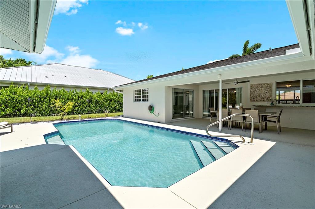 740 Orchid Drive Naples, FL 34102 - Photo 2 of 33 a view of a patio with table and chairs under an umbrella