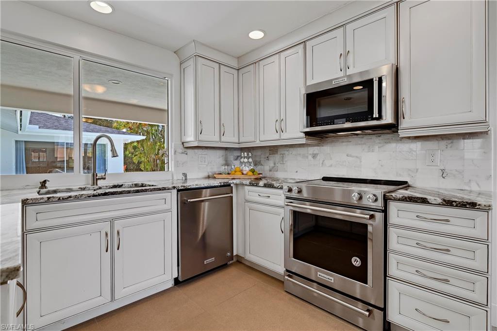 740 Orchid Drive Naples, FL 34102 - Photo 10 of 33 a kitchen with white cabinets and stainless steel appliances