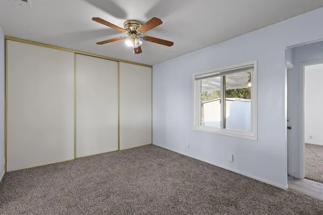 an empty room with windows and fan