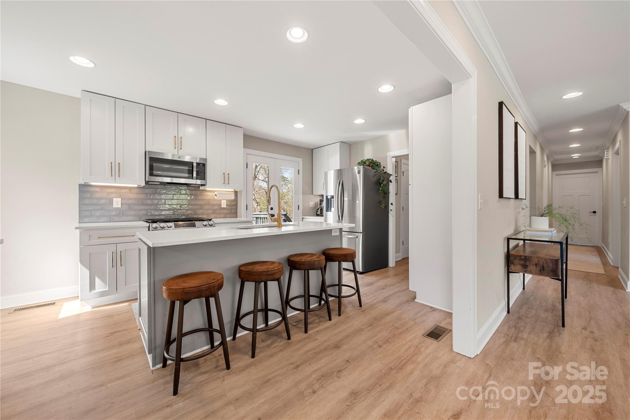 4820 Valley Stream Road Charlotte, NC 28209 - Photo 8 of 37 a kitchen with stainless steel appliances kitchen island granite countertop a refrigerator a stove a sink a dining table and chairs with wooden floor