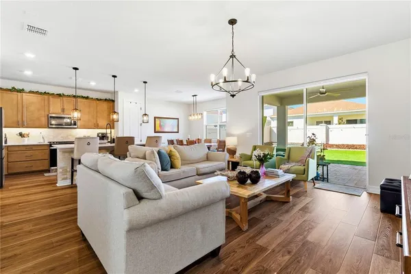 a living room with furniture kitchen view and a wooden floor