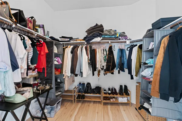 a view of walk in closet with clothes and shoes