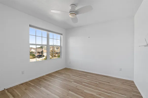 an empty room with wooden floor and windows