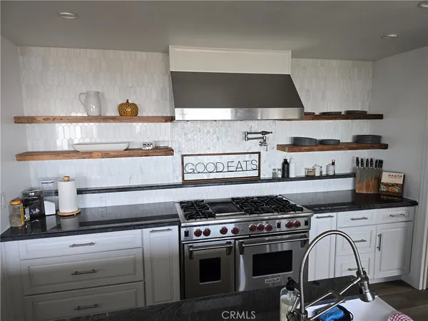 a kitchen with sink a stove and white cabinets