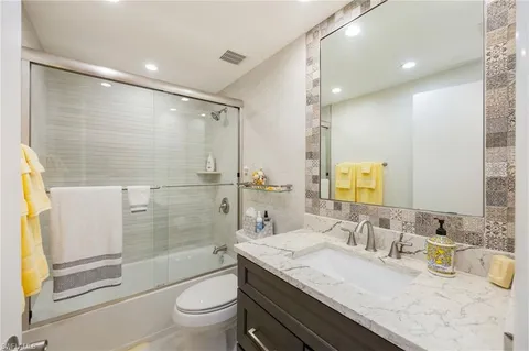 a bathroom with a granite countertop sink a toilet a mirror and shower