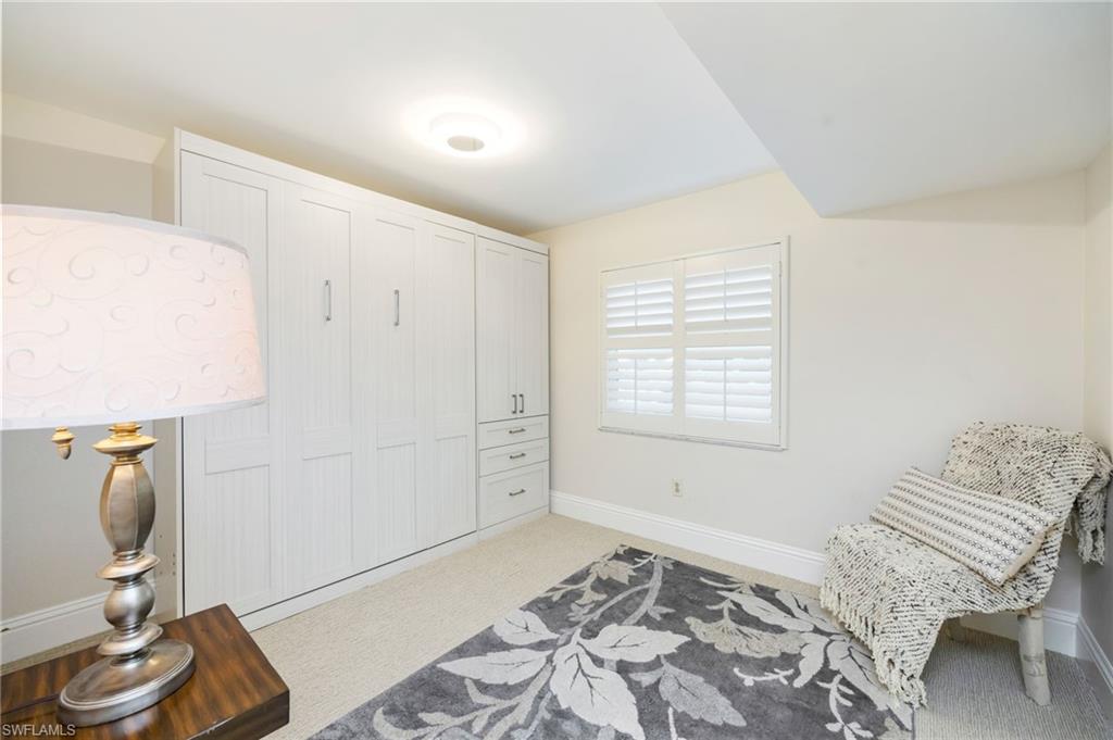 1200 Blue Point Avenue, Unit A2 Naples, FL 34102 - Photo 20 of 30 This room features light-colored carpeting, a window with white louvered shutters, and built-in white cabinetry with drawers and handles